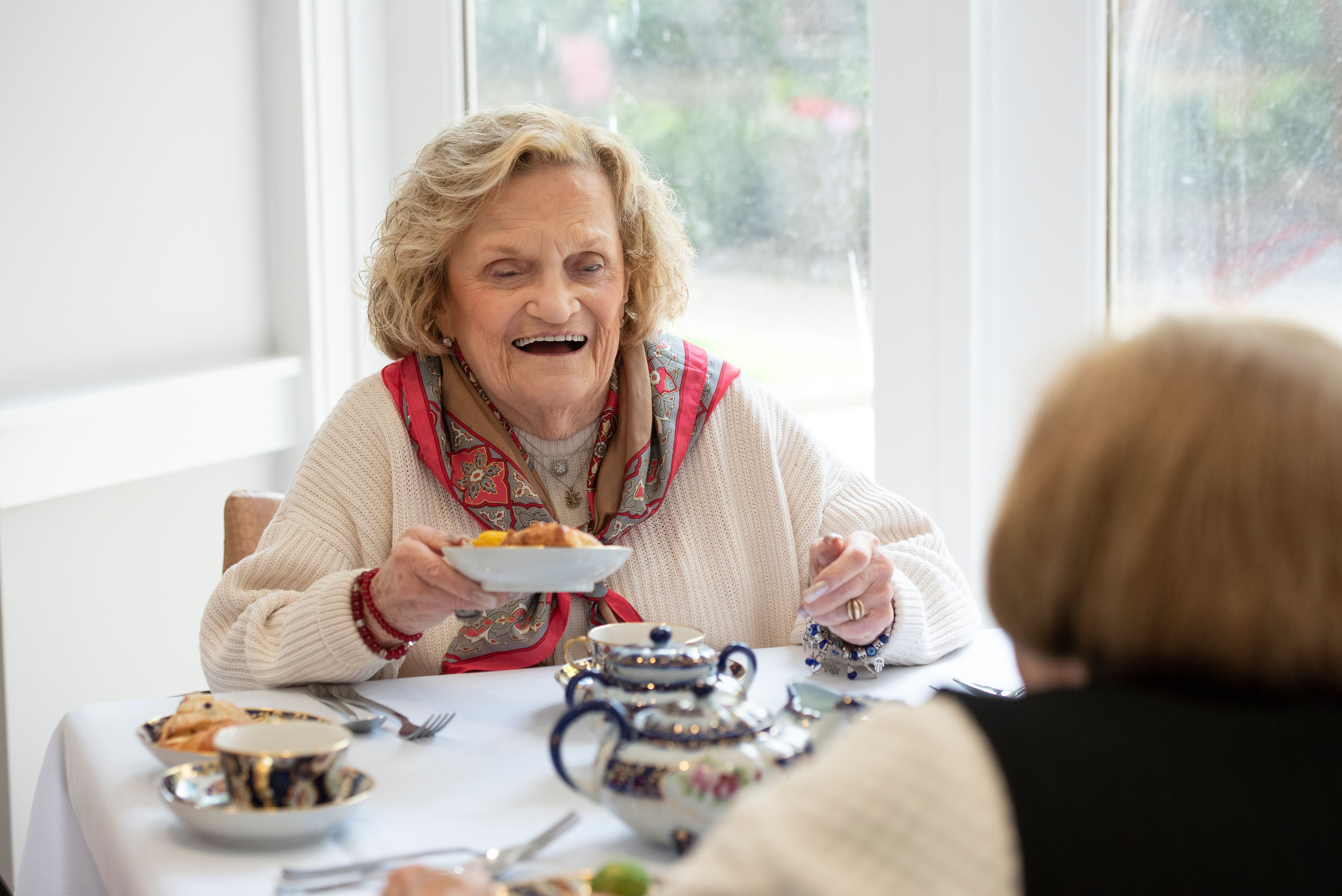 Happy woman having tea with friends at Willow Towers at United Hebrew